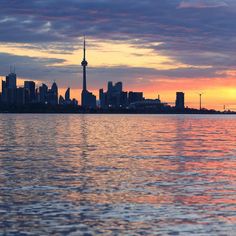 the city skyline is reflected in the water at sunset, with pink clouds and blue sky