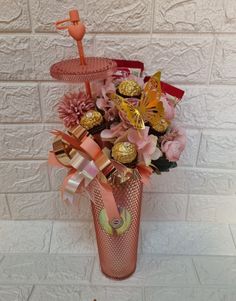 a vase filled with chocolates and flowers on top of a white countertop next to a brick wall