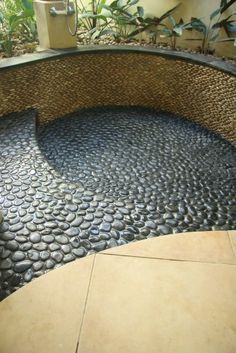 a bench made out of rocks and pebbles in a garden area with water running through it