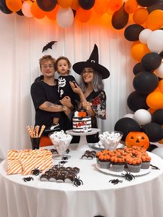 a group of people standing in front of a table filled with halloween treats and desserts