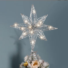 a christmas tree topper with lights on it in front of a blue wall and snowflakes