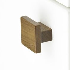 a wooden door handle on a white wall with a square shape in the center and two horizontal bars at the bottom