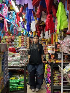 a man standing in front of a store filled with umbrellas and other colorful items