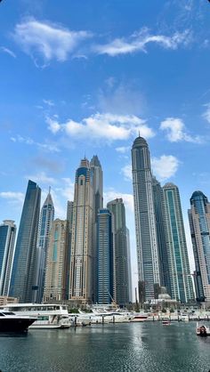 the city is surrounded by tall buildings and boats on the water in front of them