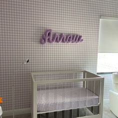 a baby's room with a crib, chair and name sign on the wall