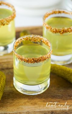 two glasses filled with green liquid and topped with sprinkles on a wooden table