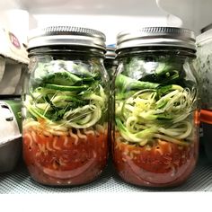 several mason jars filled with different types of vegetables and sauces on top of a counter