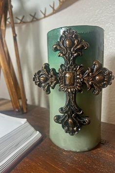 a candle with a cross on it sitting on a table next to a stack of books