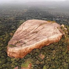 an aerial view of a large rock surrounded by trees