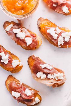 several pieces of bread with meat and cheese on them next to a bowl of oranges