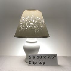 a white lamp sitting on top of a table next to a sign that says 5 x 10x75's clip top