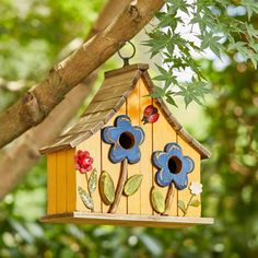 a birdhouse hanging from a tree branch with flowers painted on the outside and inside