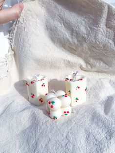 three candles sitting next to each other on top of a white cloth covered bed spread