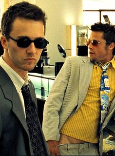 two men standing next to each other wearing suits and ties with sunglasses on their heads