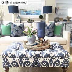 a living room with blue and white decor on the couch, coffee table and ottoman