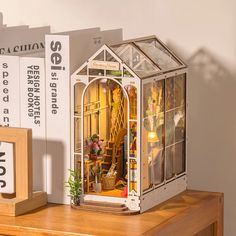 a doll house sitting on top of a wooden table next to a clock and books