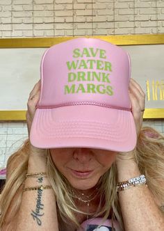 a woman wearing a pink hat with save water drink margs written on it