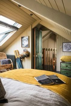 an attic bedroom with yellow bedding and wicker furniture in the foreground is a green door