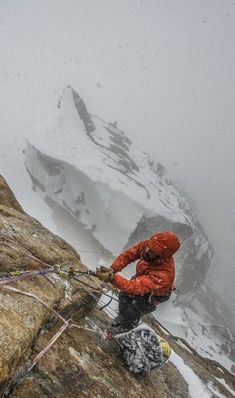 a man climbing up the side of a snow covered mountain