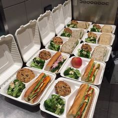 a bunch of trays filled with different types of sandwiches and salads on top of each other