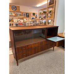 a display case with many pictures on the wall and shelves above it in a store