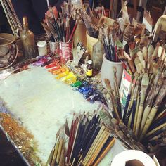 an artist's easel filled with lots of paint and brushes