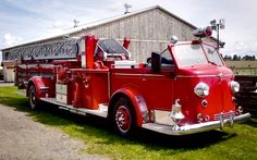 an old fire truck parked in front of a barn