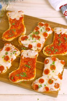 several pieces of bread with sauce and cheese on them sitting on a wooden cutting board