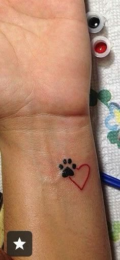 a dog paw and heart tattoo on the wrist