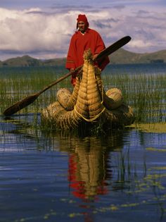 a man in a red jacket is rowing a boat