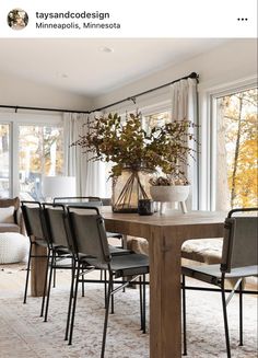 a dining room table with chairs and a vase filled with flowers on top of it