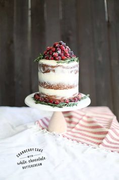 a cake with berries on top is sitting on a white plate and next to a striped napkin