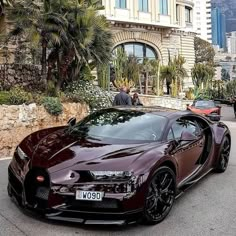 a bugatti is parked in front of a building with palm trees and people walking by