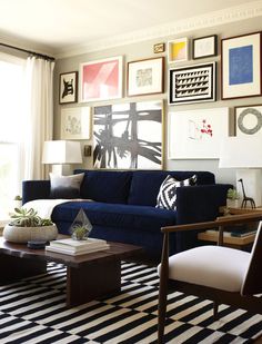 a living room with blue couches and pictures on the wall above it's coffee table