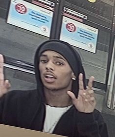 a young man wearing a hoodie and making the vulcan sign with his hands in front of him