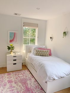 a white bed sitting in a bedroom next to a window