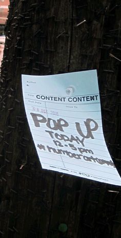 a piece of paper taped to a telephone pole with the words pop up today written on it