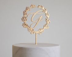 a white cake with a gold monogram on top and a single letter in the middle