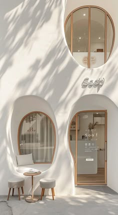 two circular windows on the side of a white building with chairs and tables in front of them