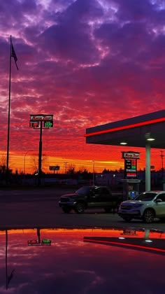 cars are parked in front of a gas station at sunset