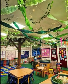 a classroom with lots of tables, chairs and hanging plants on the ceiling above them