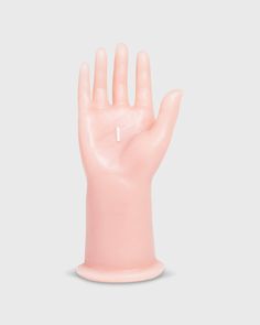 a pink plastic hand with a white cross on it's middle finger, against a gray background