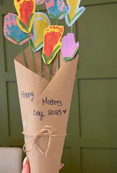 a hand holding a bouquet of flowers made out of brown paper with the words happy mothers day written on it