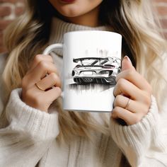 a woman holding a white coffee mug with a car on the front and back side