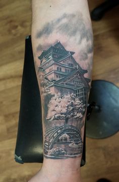 a person with a tattoo on their arm and the image of a building in the background