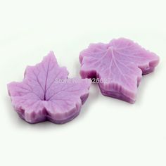 two pieces of pink soap with leaves on them, one is shaped like a leaf