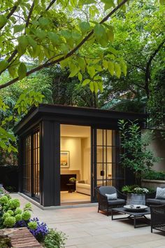 an outdoor living area with chairs, tables and a small shed in the middle of it