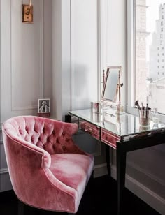 a pink velvet chair sitting in front of a desk