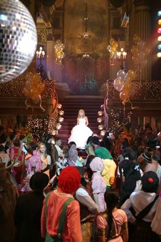 a large group of people standing in front of a stage with disco balls on it