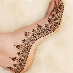 the foot is decorated with henna designs on top of white furnishing and carpet